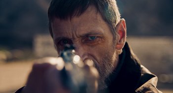 Movie still from “Too Old to Die Young” (2019), directed by Nicolas Winding Refn – A person holding a gun; Close Up shot, Over the shoulder angle