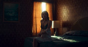 Movie still from “Too Old to Die Young” (2019), directed by Nicolas Winding Refn – A woman sitting on top of a bed next to a lamp; Medium shot, High angle