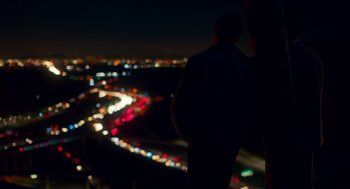 Movie still from “Too Old to Die Young” (2019), directed by Nicolas Winding Refn – A man standing on top of a building at night; Wide shot, Low angle