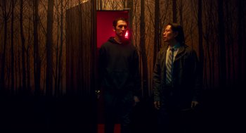 Movie still from “Too Old to Die Young” (2019), directed by Nicolas Winding Refn – Two men standing next to each other in front of trees; Medium shot, Low angle