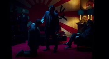 Movie still from “Too Old to Die Young” (2019), directed by Nicolas Winding Refn – A man in a suit and tie standing next to another man in a suit and tie; Wide shot, High angle