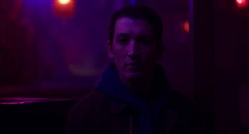 Movie still from “Too Old to Die Young” (2019), directed by Nicolas Winding Refn – A man in a jacket and a blue scarf is in a dark room; Close Up shot, Low angle