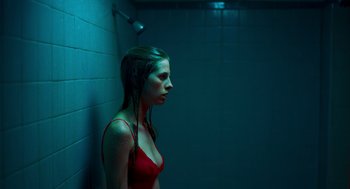 Movie still from “Too Old to Die Young” (2019), directed by Nicolas Winding Refn – A woman in a red bikini standing in a bathroom; Medium shot, High angle