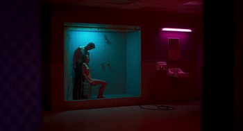 Movie still from “Too Old to Die Young” (2019), directed by Nicolas Winding Refn – A man and a woman in a room lit up with neon lights; Wide shot, Low angle