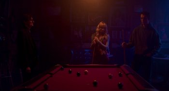 Movie still from “Too Old to Die Young” (2019), directed by Nicolas Winding Refn – A woman standing in front of a red pool table; Medium shot, Low angle