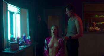Movie still from “Too Old to Die Young” (2019), directed by Nicolas Winding Refn – A woman sitting in front of a mirror while a man cuts her hair; Medium shot, Over the shoulder angle