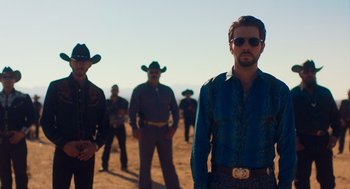 Movie still from “Too Old to Die Young” (2019), directed by Nicolas Winding Refn – A group of men standing on top of a dirt field; Medium shot, Low angle
