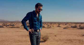 Movie still from “Too Old to Die Young” (2019), directed by Nicolas Winding Refn – A man standing in the middle of an empty field; Medium shot, Low angle