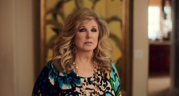 Movie still from “Too Old to Die Young” (2019), directed by Nicolas Winding Refn – A person with long hair wearing a dress; Close Up shot, Over the shoulder angle