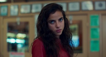 Movie still from “Too Old to Die Young” (2019), directed by Nicolas Winding Refn – A woman with long dark brown hair wearing a red shirt; Close Up shot, Low angle