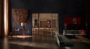 Movie still from “Too Old to Die Young” (2019), directed by Nicolas Winding Refn – A person is standing in a living room with glass doors; Extreme Wide shot, High angle