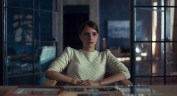 Movie still from “Too Old to Die Young” (2019), directed by Nicolas Winding Refn – A woman sitting at a table in front of a window; Medium shot, Over the shoulder angle