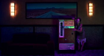 Movie still from “Too Old to Die Young” (2019), directed by Nicolas Winding Refn – A woman standing in front of an old vending machine; Wide shot, Low angle