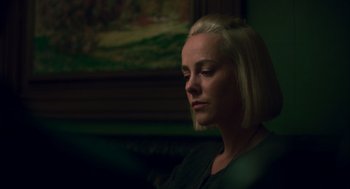 Movie still from “Too Old to Die Young” (2019), directed by Nicolas Winding Refn – A woman sitting in front of a painting looking down; Close Up shot, Over the shoulder angle