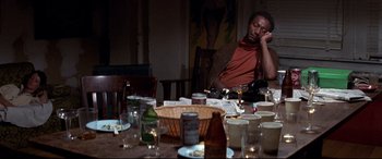 Movie still from “Tootsie” (1982), directed by Sydney Pollack – A man sitting at a dinner table with a bottle of beer; Medium shot, High angle