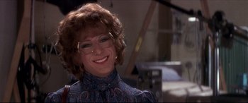 Movie still from “Tootsie” (1982), directed by Sydney Pollack – A woman wearing glasses and smiling for the camera; Close Up shot, Over the shoulder angle