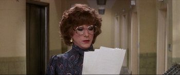 Movie still from “Tootsie” (1982), directed by Sydney Pollack – A woman in glasses is holding papers in her hands; Close Up shot, Over the shoulder angle