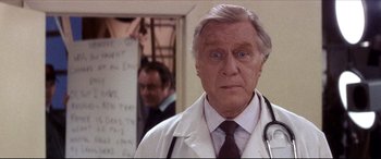 Movie still from “Tootsie” (1982), directed by Sydney Pollack – An older man wearing a white lab coat and a tie; Close Up shot, Low angle