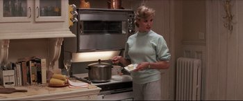 Movie still from “Tootsie” (1982), directed by Sydney Pollack – A woman standing in front of an oven holding a pan; Medium shot, Over the shoulder angle