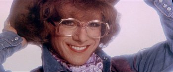 Movie still from “Tootsie” (1982), directed by Sydney Pollack – A person wearing glasses and smiling; Close Up shot, High angle
