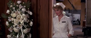 Movie still from “Tootsie” (1982), directed by Sydney Pollack – A woman in a nurse's uniform standing in front of a door; Medium shot, Over the shoulder angle