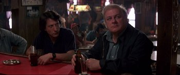 Movie still from “Tootsie” (1982), directed by Sydney Pollack – Two men sitting at a table in front of a glass of beer; Medium shot, Over the shoulder angle