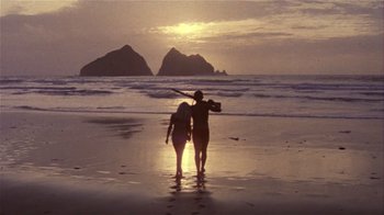 Movie still from “Top Secret!” (1984), directed by Jim Abrahams – Two people walking on the beach at sunset; Wide shot, Low angle