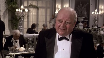 Movie still from “Top Secret!” (1984), directed by Jim Abrahams – An older man wearing a tuxedo in front of a table; Close Up shot, Over the shoulder angle