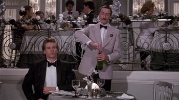 Movie still from “Top Secret!” (1984), directed by Jim Abrahams – A man in a tuxedo is pouring champagne into a glass; Medium shot, Low angle