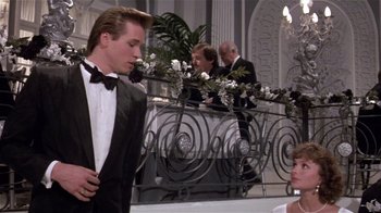 Movie still from “Top Secret!” (1984), directed by Jim Abrahams – A group of people in tuxedos standing in front of a railing; Medium shot, Low angle