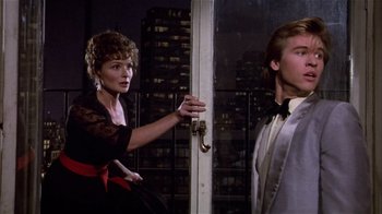Movie still from “Top Secret!” (1984), directed by Jim Abrahams – A man and a woman standing next to each other in front of an open door; Medium shot, Low angle
