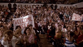 Movie still from “Top Secret!” (1984), directed by Jim Abrahams – A crowd of people sitting and standing in front of a crowd; Wide shot, High angle