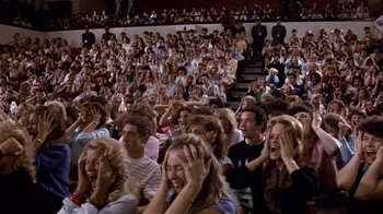 Movie still from “Top Secret!” (1984), directed by Jim Abrahams – A crowd of people sitting in a stadium watching a show; Wide shot, High angle