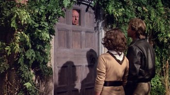 Movie still from “Top Secret!” (1984), directed by Jim Abrahams – Two people standing in front of an open door; Medium shot, Over the shoulder angle