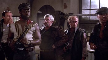 Movie still from “Top Secret!” (1984), directed by Jim Abrahams – A group of men standing next to each other in a room; Medium shot, Low angle