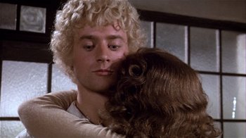 Movie still from “Top Secret!” (1984), directed by Jim Abrahams – A man holding a dog in his arms; Close Up shot, Over the shoulder angle