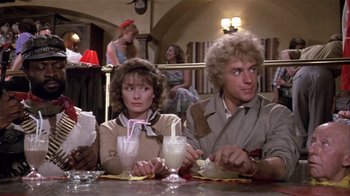 Movie still from “Top Secret!” (1984), directed by Jim Abrahams – A man and a woman sitting at a table with drinks in front of them; Medium shot, Over the shoulder angle