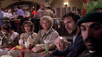 Movie still from “Top Secret!” (1984), directed by Jim Abrahams – A group of people sitting at a table with drinks; Medium shot, High angle