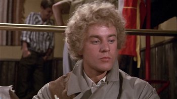 Movie still from “Top Secret!” (1984), directed by Jim Abrahams – A man with a blonde curly hair and a brown jacket; Close Up shot, Low angle
