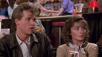 Movie still from “Top Secret!” (1984), directed by Jim Abrahams – A man and a woman sitting at a table in a restaurant; Medium shot, Over the shoulder angle