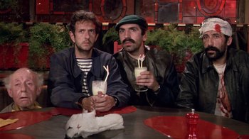 Movie still from “Top Secret!” (1984), directed by Jim Abrahams – A couple of men sitting at a table with drinks; Medium shot, High angle