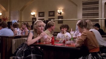 Movie still from “Top Secret!” (1984), directed by Jim Abrahams – A group of people sitting at a table in a restaurant; Medium shot, Over the shoulder angle