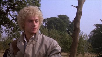 Movie still from “Top Secret!” (1984), directed by Jim Abrahams – A man with blonde curly hair is standing in a field; Close Up shot, Low angle
