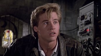 Movie still from “Top Secret!” (1984), directed by Jim Abrahams – A young man with long blonde hair wearing a leather jacket; Close Up shot, Low angle