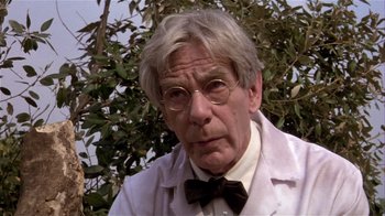 An older man wearing a white lab coat and bow tie