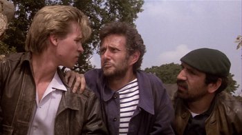 Movie still from “Top Secret!” (1984), directed by Jim Abrahams – A group of men standing next to each other on a field; Medium shot, Low angle