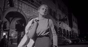 Movie still from “Touch of Evil” (1958), directed by Orson Welles – A black - and - white photo of a woman walking down a street; Medium shot, Low angle