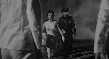 Movie still from “Touch of Evil” (1958), directed by Orson Welles – A man and a woman walking on a beach; Medium shot, Low angle
