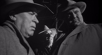 Movie still from “Touch of Evil” (1958), directed by Orson Welles – A group of men standing next to each other; Close Up shot, Low angle