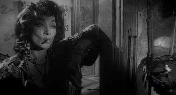 Movie still from “Touch of Evil” (1958), directed by Orson Welles – A black and white photo of a woman smoking a cigarette; Close Up shot, Low angle